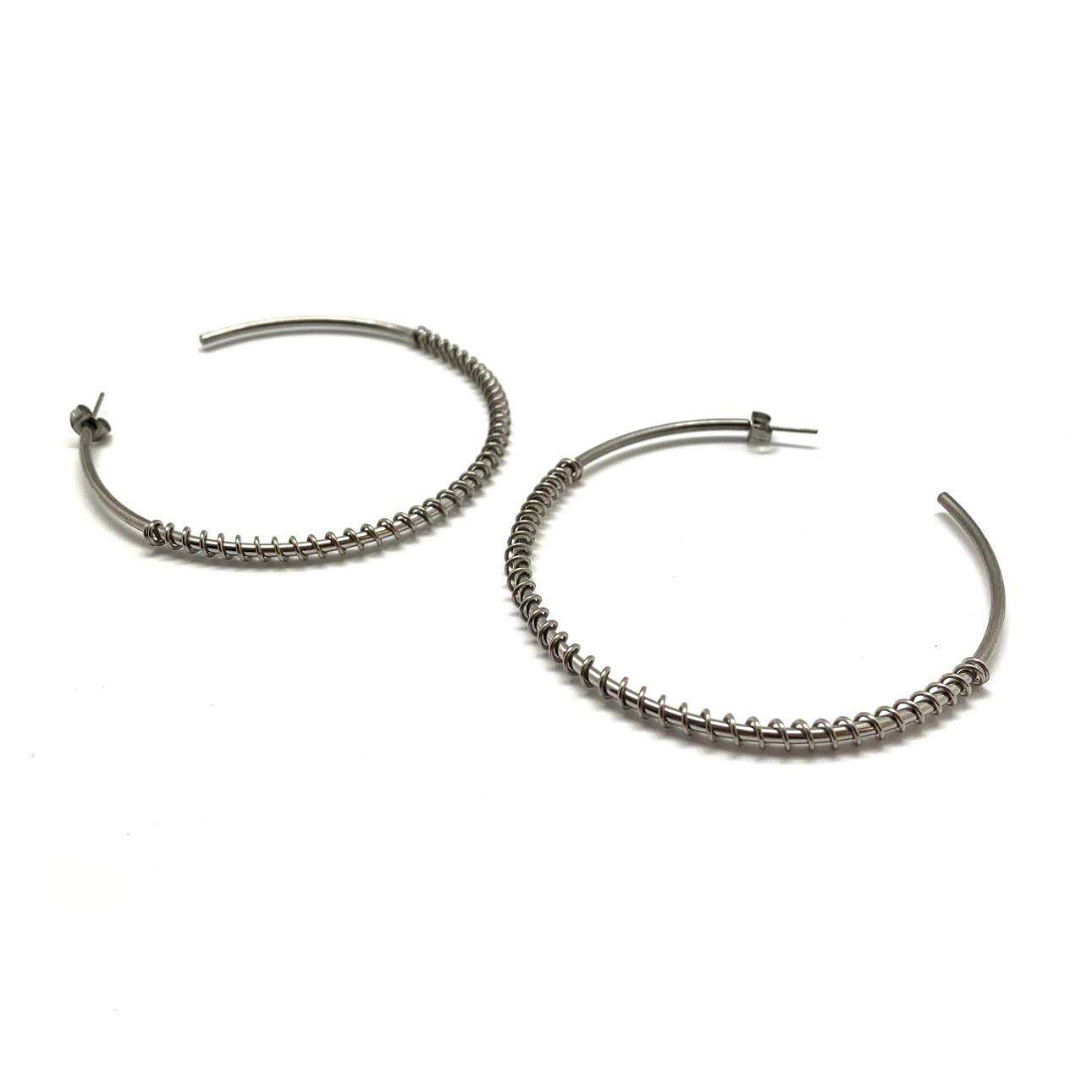 Polished stainless steel spiral hoop earrings in silver with a fluid, contemporary design.